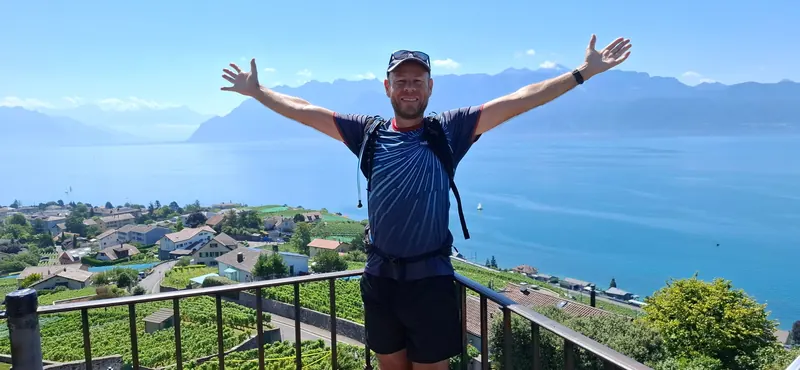 Sam en randonnée : les bras ouverts face au lac et aux montagnes